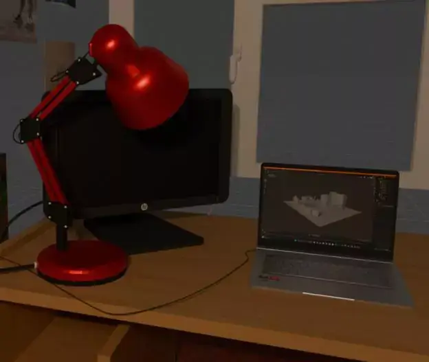 A close up of the desk, where a lamp, monitor and laptop are visible